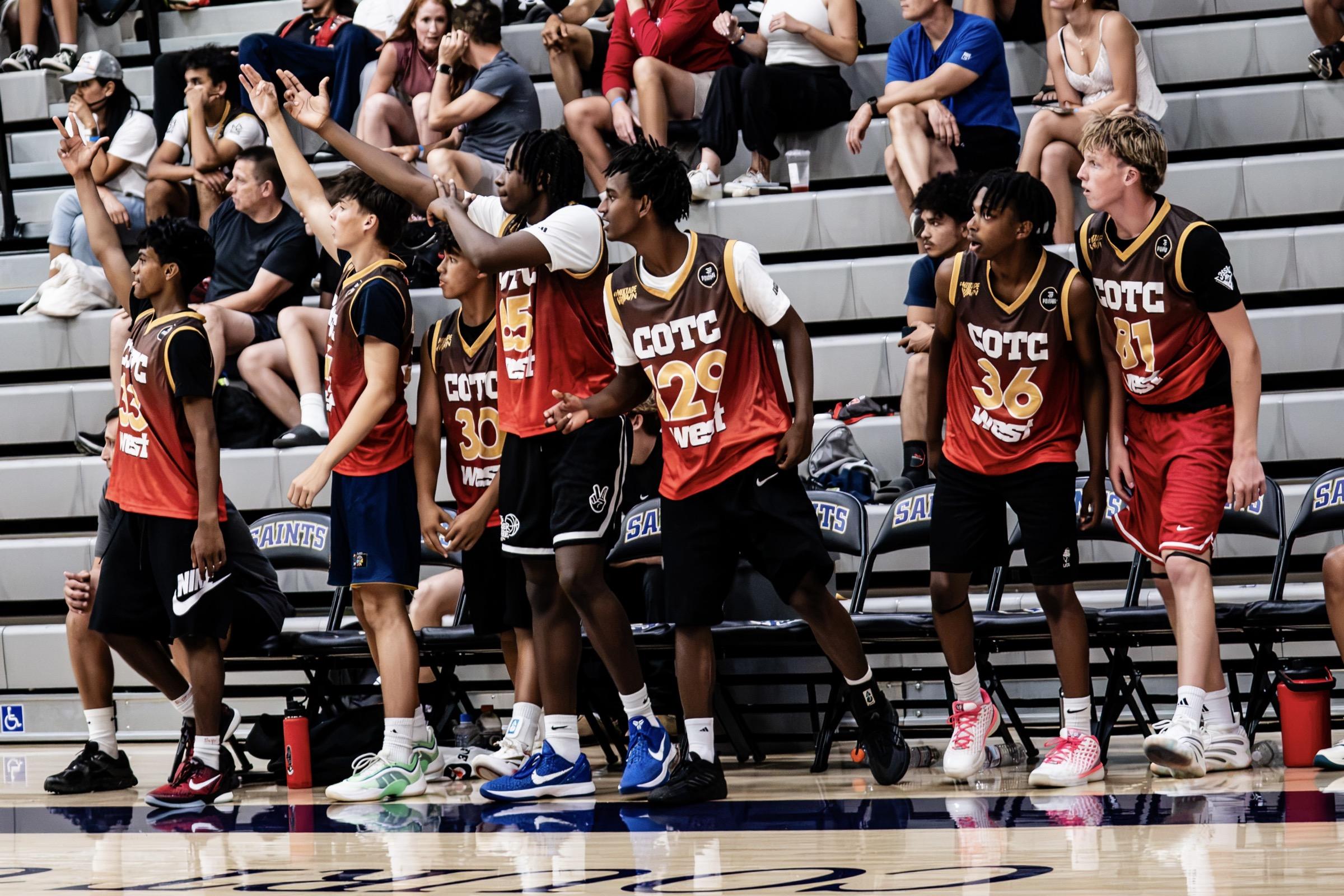 A row of COTC West players in red and brown jerseys reacting courtside, arms raised, with the crowd cheering behind them.